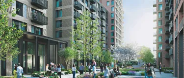 Häuserzeile mit begrüntem Fußgänger-Bereich und Menschen. 