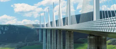 Moderne Bruecke ueber einem Tal vor Huegeln.