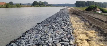 Wasserbausteine am Ufer eines Flusses nebst Sand und Erde.