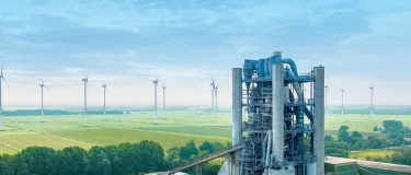 Zementwerk mit Windenergieanlagen im Hintergrund.
