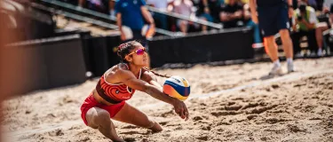 Beachvolleyballspielerin nimmt einen Ball an.