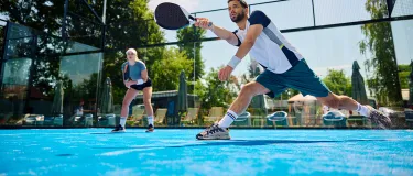 Padelspieler auf einem Padelfeld bei der Ballannahme.
