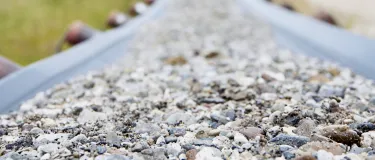 Förderband mit Kies zwischen Wiesen.