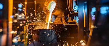 Glühende Flüssigkeit wird in ein Behältnis gegossen. 