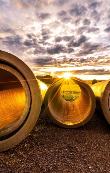 Drei Betonrohre auf dem Boden mit Abendsonne.