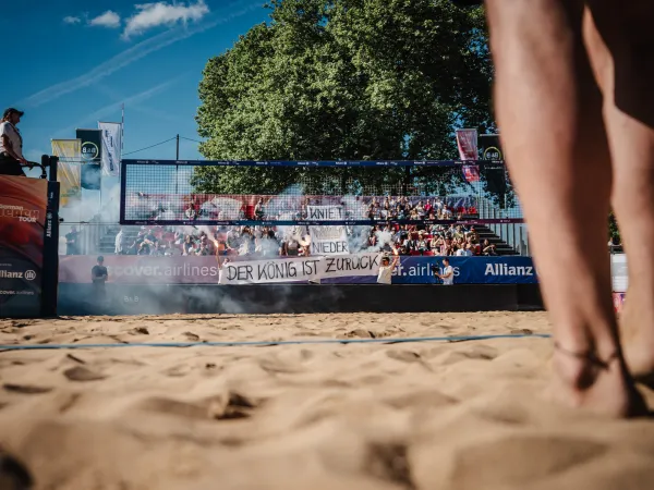 Beachvolleyballspiel-Szene auf einem Beachvolleyplatz mit Tribuehne im Hintergrund.jpg