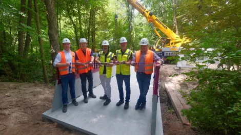 cpc Modulbruecke in einem Wald mit Menschen und Kran im Hintergrund.