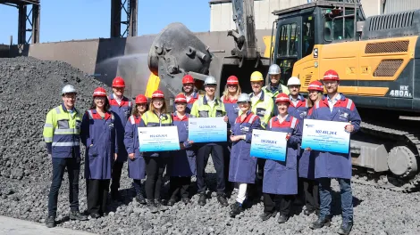 Gruppenfoto von Menschen mit Bauhelmen vor einem Bagger