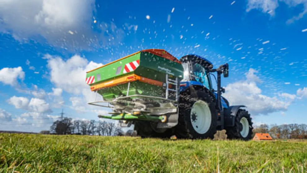 Traktor der auf einem Feld Kalk oder Samen verstreut