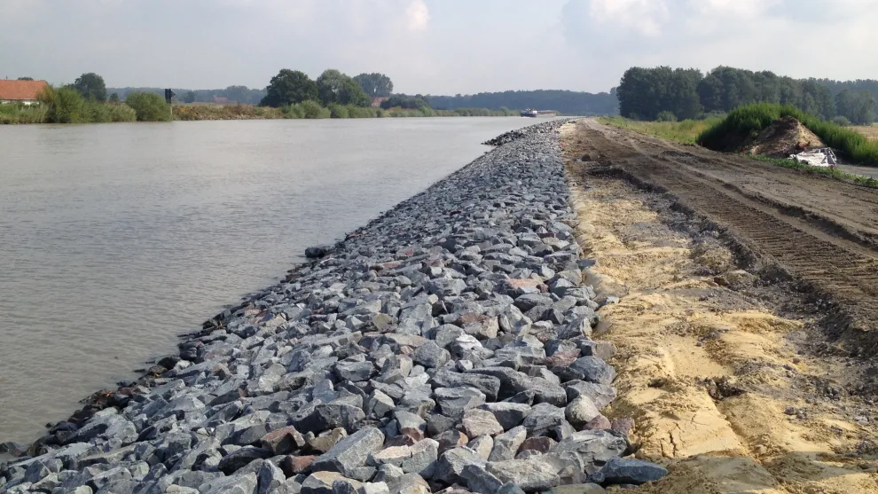 Wasserbausteine am Ufer eines Flusses nebst Sand und Erde.