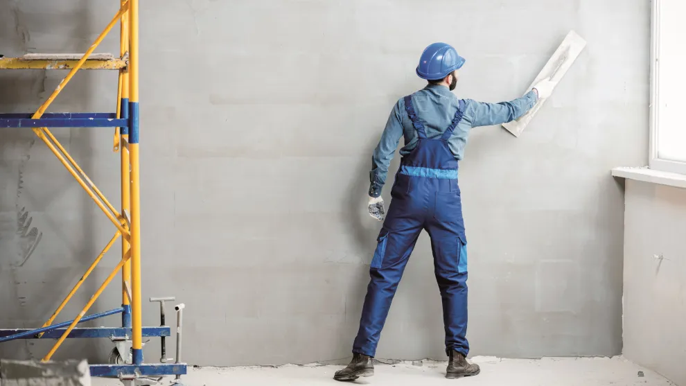 Putzer verputzt eine Wand.