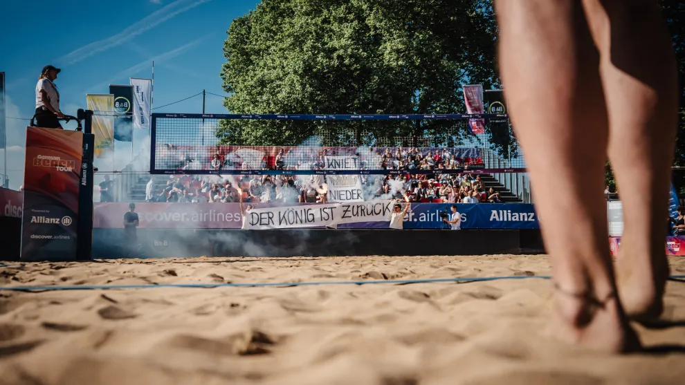 Beachvolleyballspiel-Szene auf einem Beachvolleyplatz mit Tribuehne im Hintergrund.jpg