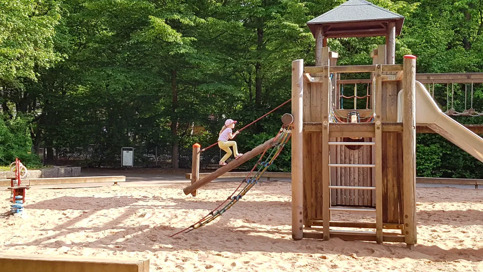Spielgerüst auf einem Spielplatz mit einem Mädchen, das darauf klettert