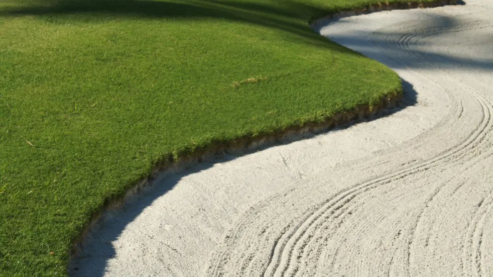 Golfplatz herangezoomt - Rasenkante an Sandkante.