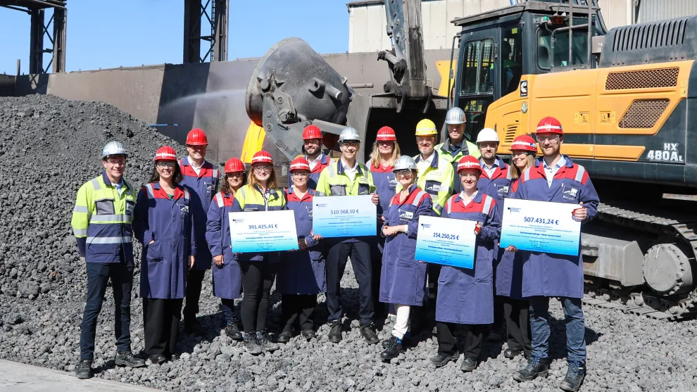 Gruppenfoto von Menschen mit Bauhelmen vor einem Bagger