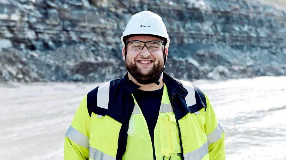 Junger Mann mit einer Anstoßkappe vor einer Felsenwand.