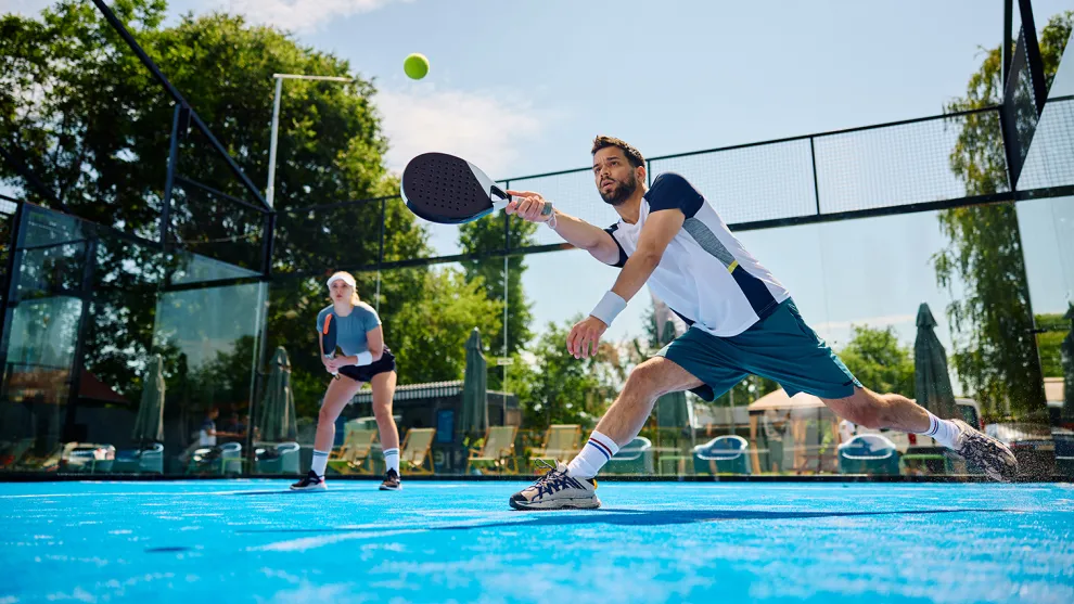Padelspieler auf einem Padelfeld bei der Ballannahme.