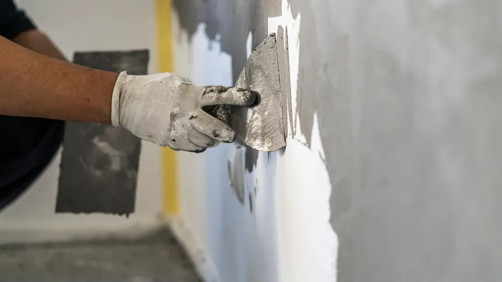 Auftragen von Putz auf eine Wand mittels einer Kelle.