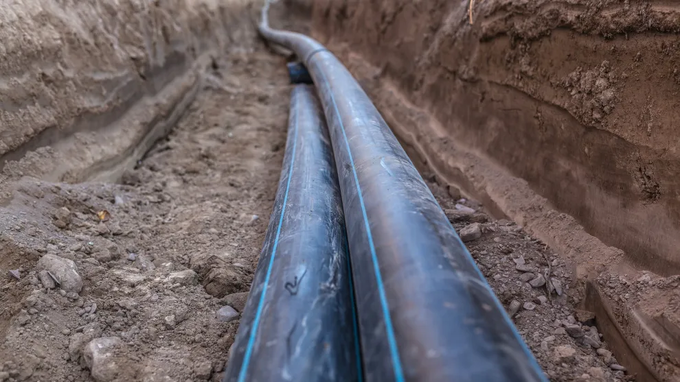 Zwei Leitungen in einem Erd-Graben.