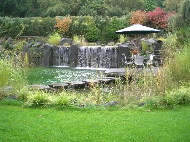 Teich mit Wasserfall hinter einer Wiese