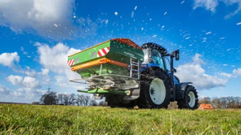 Traktor der auf einem Feld Kalk oder Samen verstreut