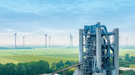 Zementwerk mit Windenergieanlagen im Hintergrund.