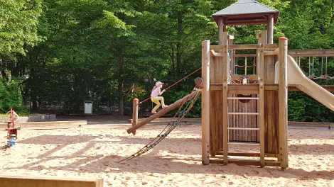 Spielgerüst auf einem Spielplatz mit einem Mädchen, das darauf klettert