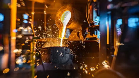 Glühende Flüssigkeit wird in ein Behältnis gegossen. 