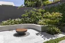 Bild eines Gartens mit einem Rasen einer Steinmauer und einem Haus