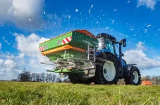 Traktor der auf einem Feld Kalk oder Samen verstreut