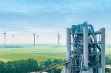 Zementwerk mit Windenergieanlagen im Hintergrund.