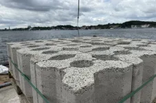 Stapel mit Betonwaren vor Wasser.