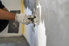 Auftragen von Putz auf eine Wand mittels einer Kelle.